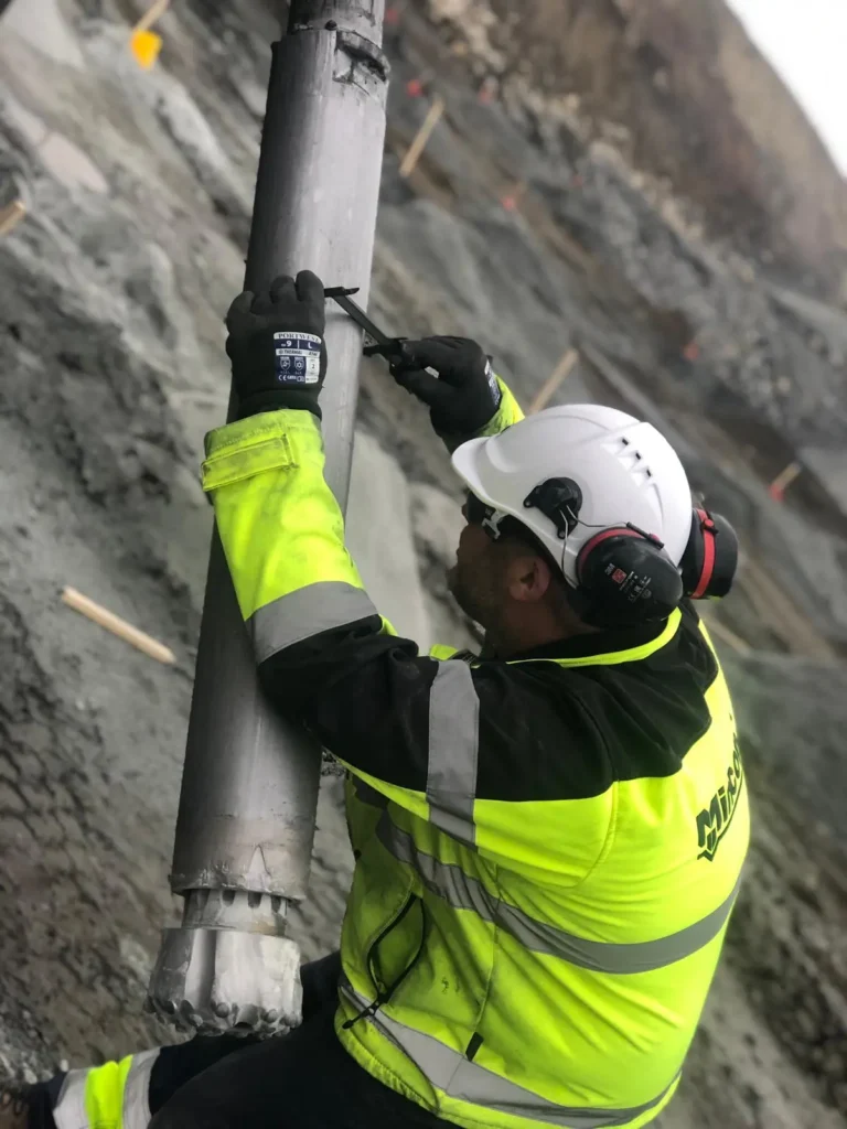 Mincon technician inspecting a DTH hammer and drill bit on a drill string to help extend hammer life in blast-hole drilling